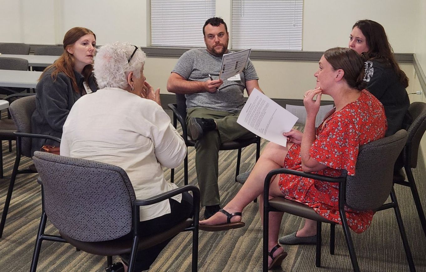 5 adult learners in a small group discussing an ethics case